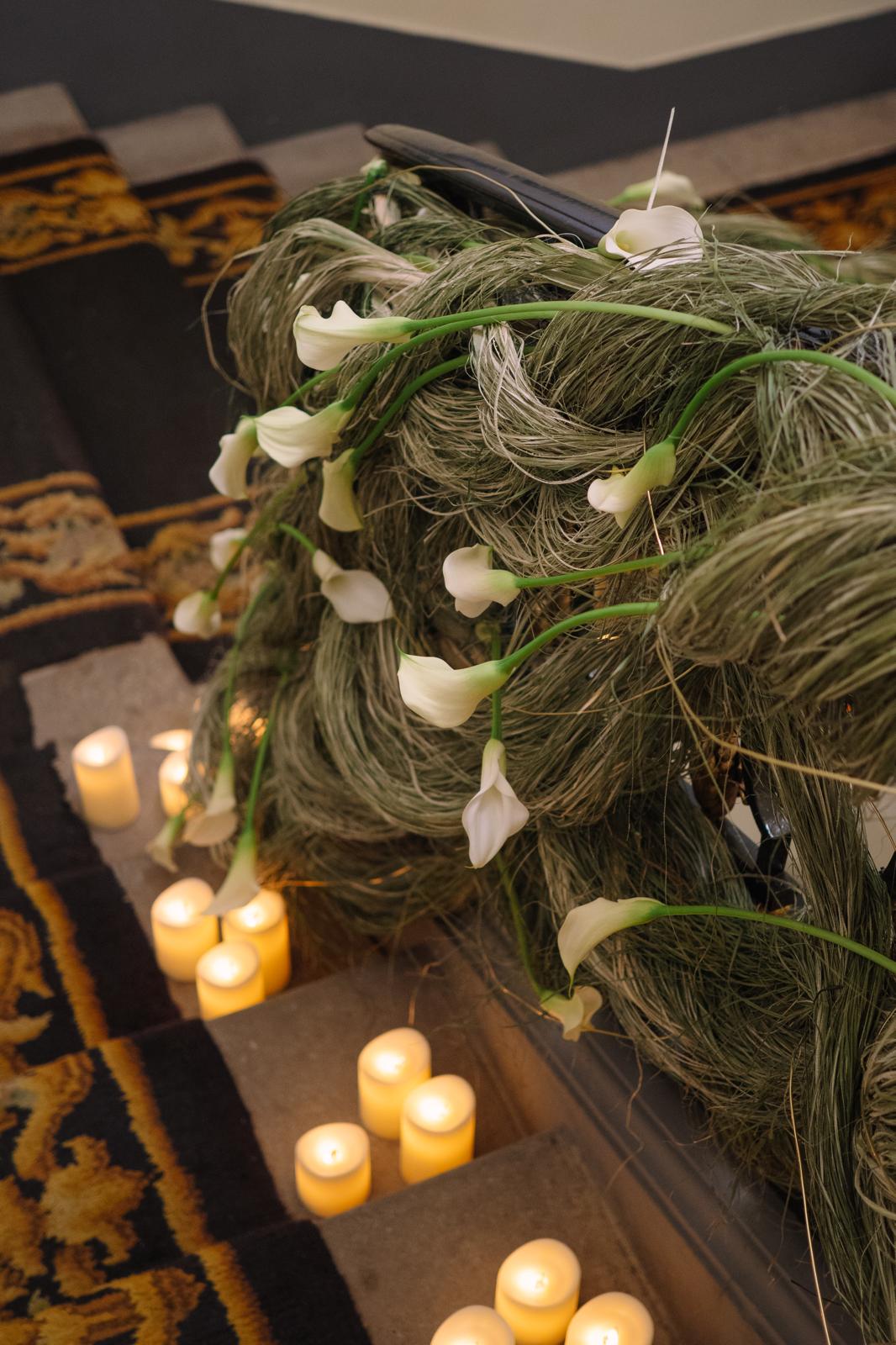 Decoración floral de boda en barandilla con calas blancas, fibras naturales y velas en la escalera