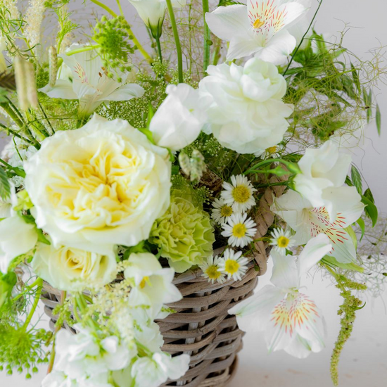 Arreglo floral blanco y verde con rosas, alstroemeria y margaritas en cesta de mimbre