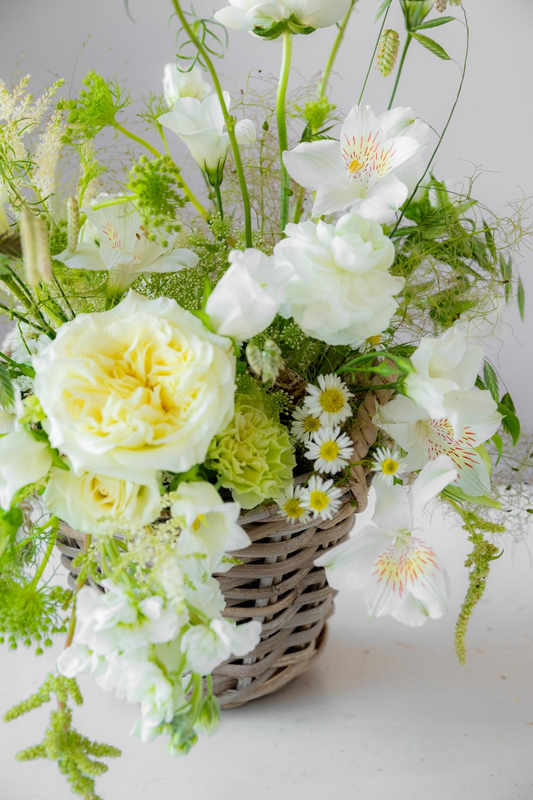 Arreglo floral blanco y verde con rosas, alstroemeria y margaritas en cesta de mimbre