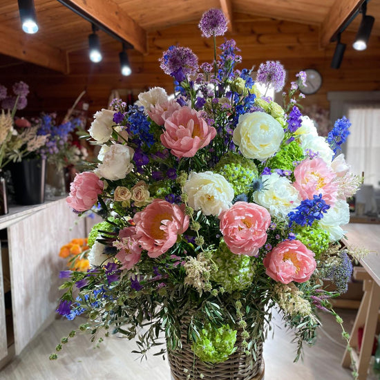 Arreglo floral grande en cesta con peonías rosas y blancas en taller de floristería