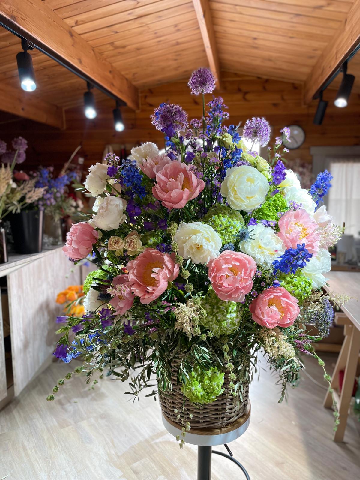 Arreglo floral grande en cesta con peonías rosas y blancas en taller de floristería