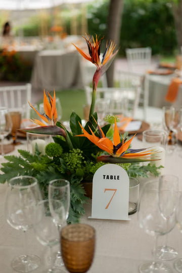 Centro de mesa con flores de ave del paraíso naranjas y verdes tropicales, decoración de boda