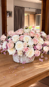 Centro de mesa con rosas blancas y rosas en cesta de mimbre sobre mesa de madera