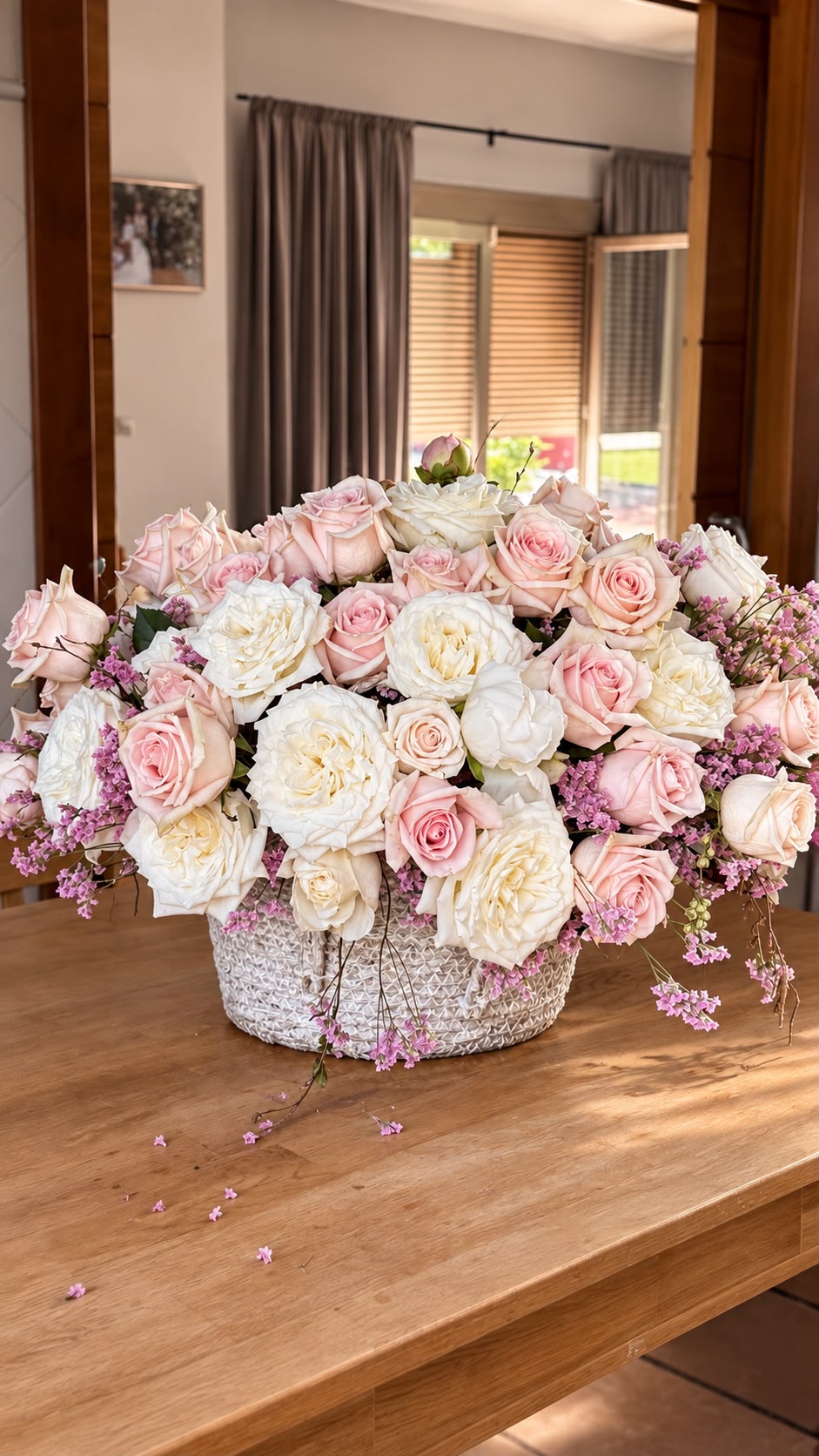 Centro de mesa con rosas blancas y rosas en cesta de mimbre sobre mesa de madera