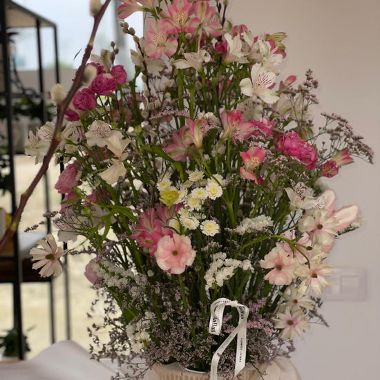 Detalle de cesta de flores con alstroemerias rosas, claveles, margaritas blancas, limonium y ramas de sauce