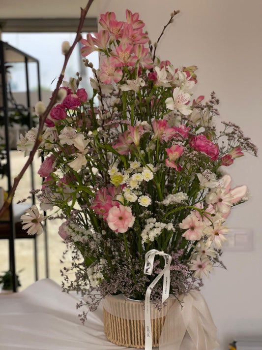 Detalle de cesta de flores con alstroemerias rosas, claveles, margaritas blancas, limonium y ramas de sauce