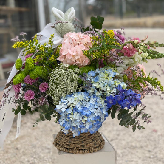 Cesta de flores con hortensias azules y rosas, delphinium, ammi blanco, crisantemos verdes y lilas y solidago