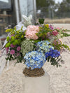 Cesta de flores con hortensias azules y rosas, delphinium, ammi blanco, crisantemos verdes y lilas y solidago