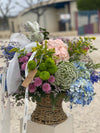 Cesta de mimbre con hortensias azules y rosas, crisantemos verdes y lilas, ammi, solidago y lazos de ANHUÁ Flowers