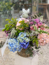 Cesta de flores con hortensias azules y rosas, bocas de dragón, delphinium, crisantemos y solidago