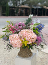 Cesta de flores con hortensias rosas, crisantemos morados, bocas de dragón, delphinium azul, solidago y eucalipto