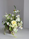 Cesta de mimbre con rosas blancas y alstroemeria, vista lateral sobre fondo gris