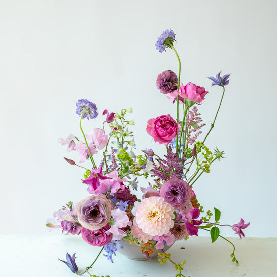 Composición floral en jarrón con dalia, ranúnculos morados y escabiosa, estilo orgánico