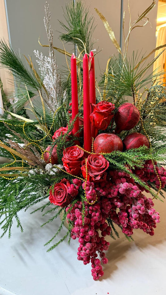 Composición navideña con velas rojas, rosas rojas escarchadas, granadas, bayas rojas, ramas de pino y guirnalda dorada