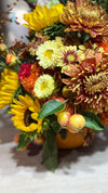 Detalle de composición otoñal con girasoles, crisantemos amarillos y cobrizos, celosía naranja y manzanas ornamentales