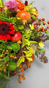 Detalle de composición otoñal con granadas, gerbera roja, lisianthus rosa, bayas naranjas y crisantemo verde
