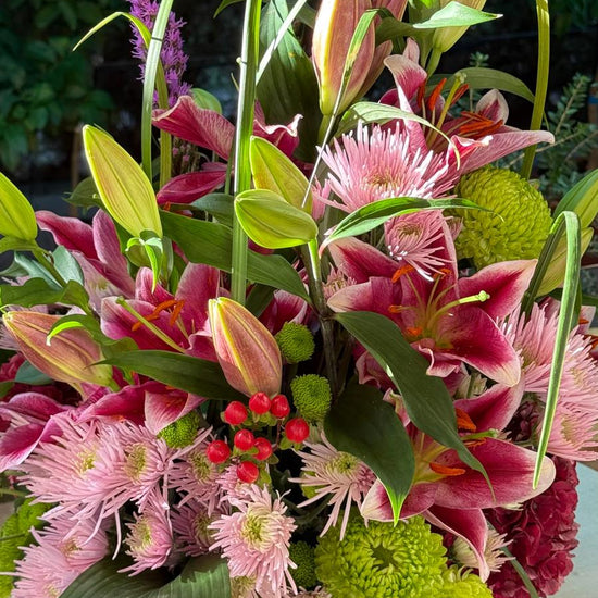 Detalle del centro floral con lilium rosa, crisantemos rosas y verdes, hypericum rojo y liatris morado
