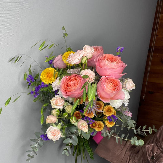 Éclat Rosé — ramo con rosas coral, cardo azul y flores naranjas otoñales