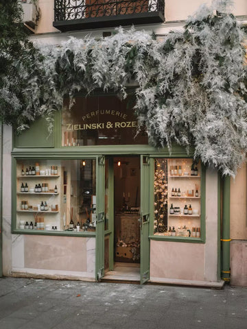 Fachada de tienda con decoración vegetal blanca y escaparate de perfumería