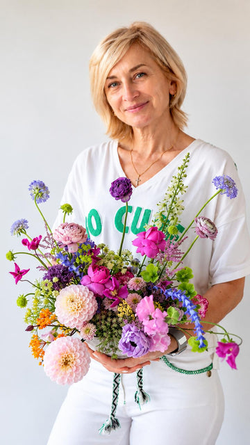 Mujer rubia sosteniendo un ramo de flores variadas de colores