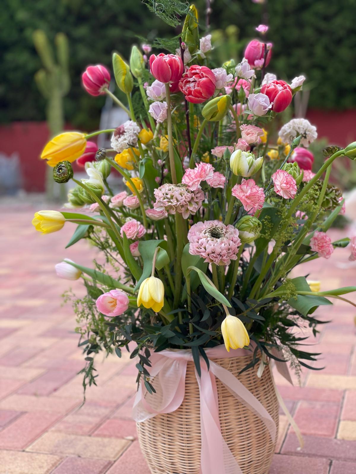 Jardín de Alegría — cesta de mimbre con tulipanes, claveles rosas y cinta de tul