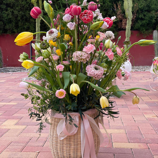 Jardín de Alegría — cesta completa con tulipanes amarillos y rosas sobre suelo de piedra