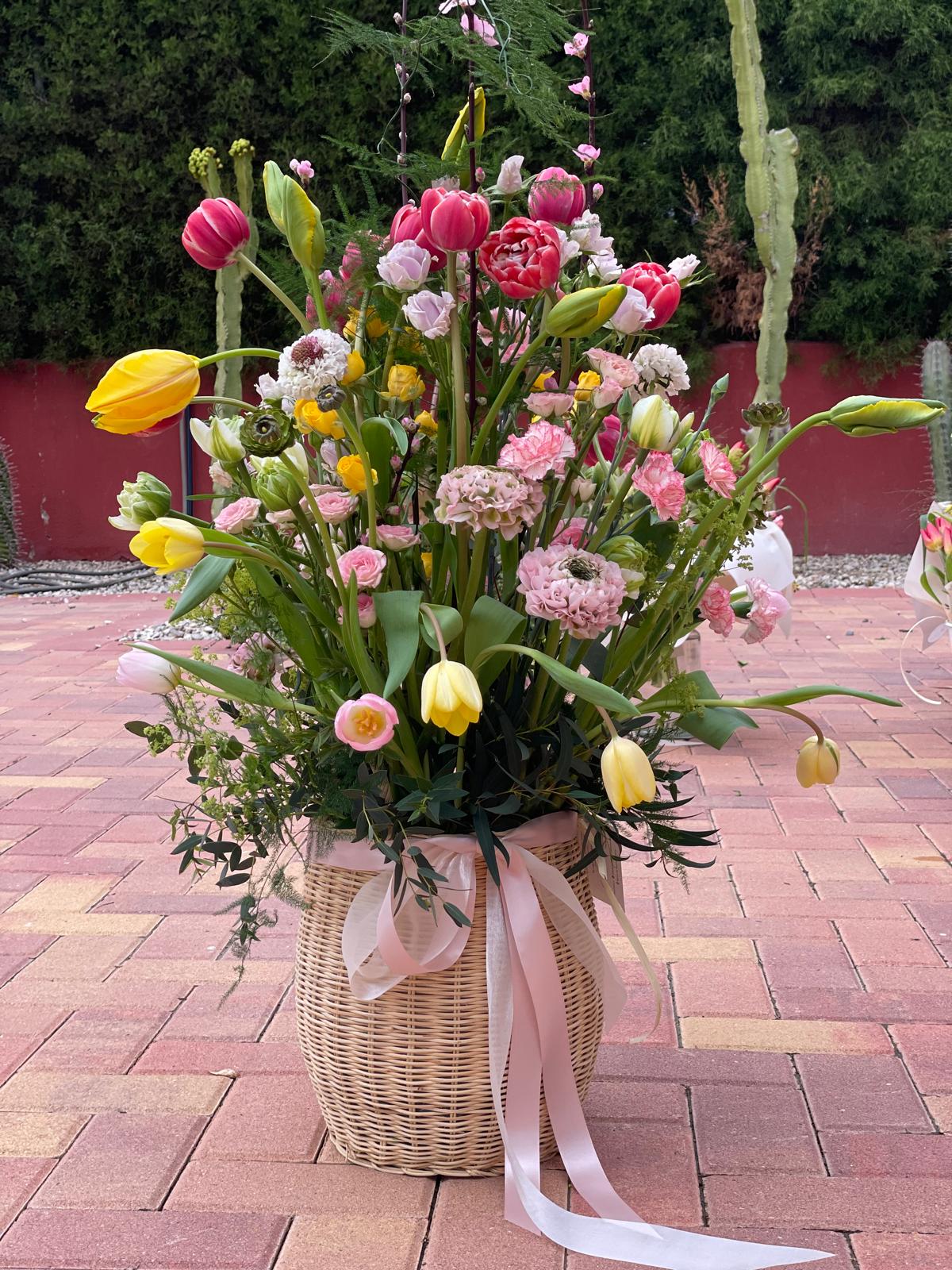 Jardín de Alegría — cesta completa con tulipanes amarillos y rosas sobre suelo de piedra