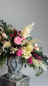 Jarrón escultórico con rostro y arreglo floral de rosas y plumas de pampas