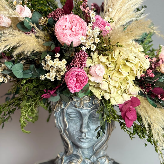 Jarrón con rostro de mujer con rosas rosas, hortensia verde y plumas de pampas
