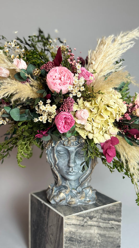 Jarrón con rostro de mujer con rosas rosas, hortensia verde y plumas de pampas