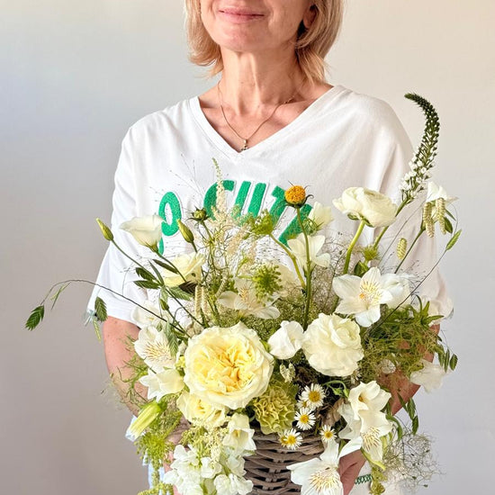 Mujer sonriente con cesta de flores blancas y amarillas en cesta de mimbre