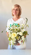 Mujer sonriente con cesta de flores blancas y amarillas en cesta de mimbre