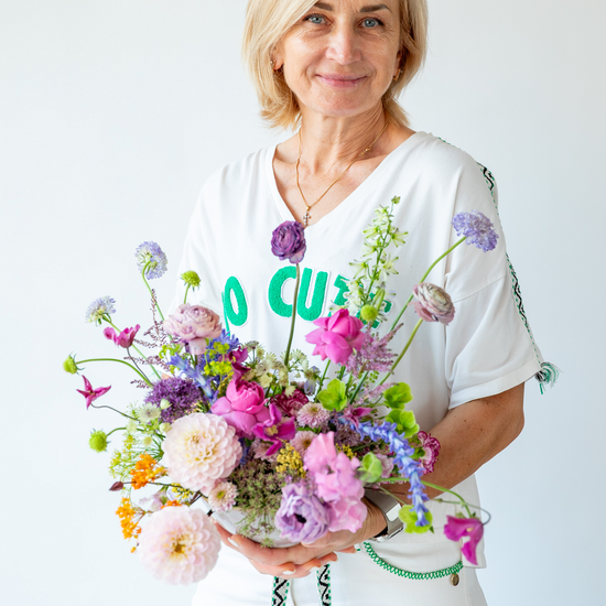 Mujer sonriente con ramo colorido de dalias, ranúnculos y flores moradas y rosas