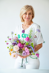 Mujer sonriente con ramo colorido de dalias, ranúnculos y flores moradas y rosas