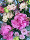 Primer plano de peonías fucsia con gotas de agua, lisianthus crema y crisantemos rosas