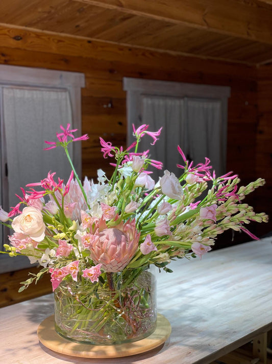 Pink Reverie — composición con protea rosa, orquídeas cymbidium y nerina fucsia