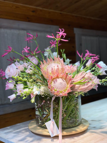 Pink Reverie — primer plano de protea rosa en jarrón con nerina fucsia