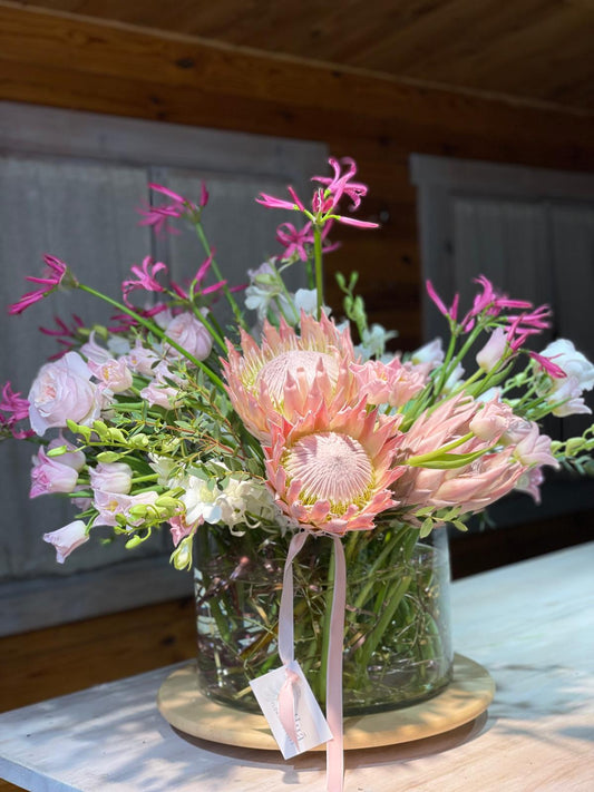 Pink Reverie — primer plano de protea rosa en jarrón con nerina fucsia