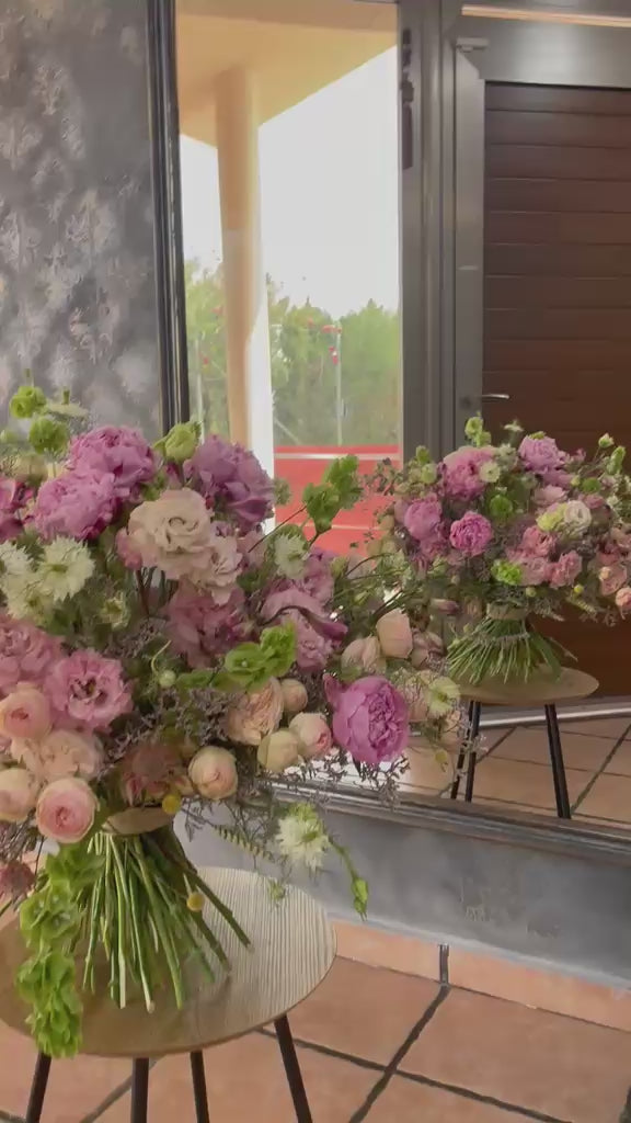 Vídeo de dos ramos de rosas y lisianthus rosas en jarrones junto a ventanal
