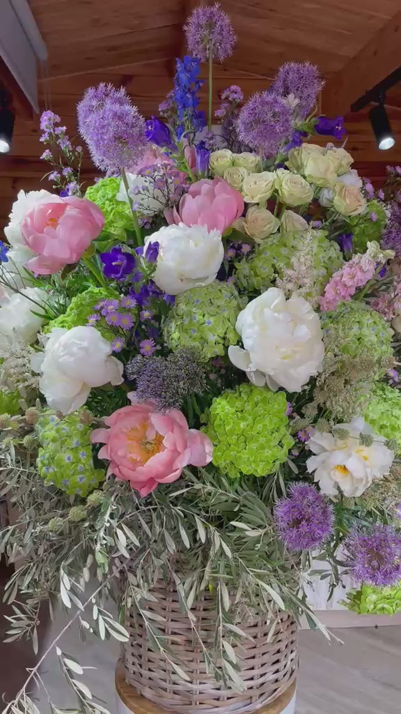 Vídeo de arreglo floral con peonías, hortensias verdes y allium en cesta de mimbre