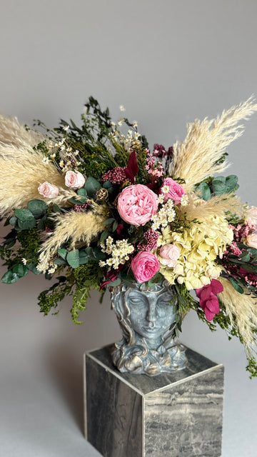 Primer plano de arreglo floral con rosas rosas, hortensia y plumas de pampas