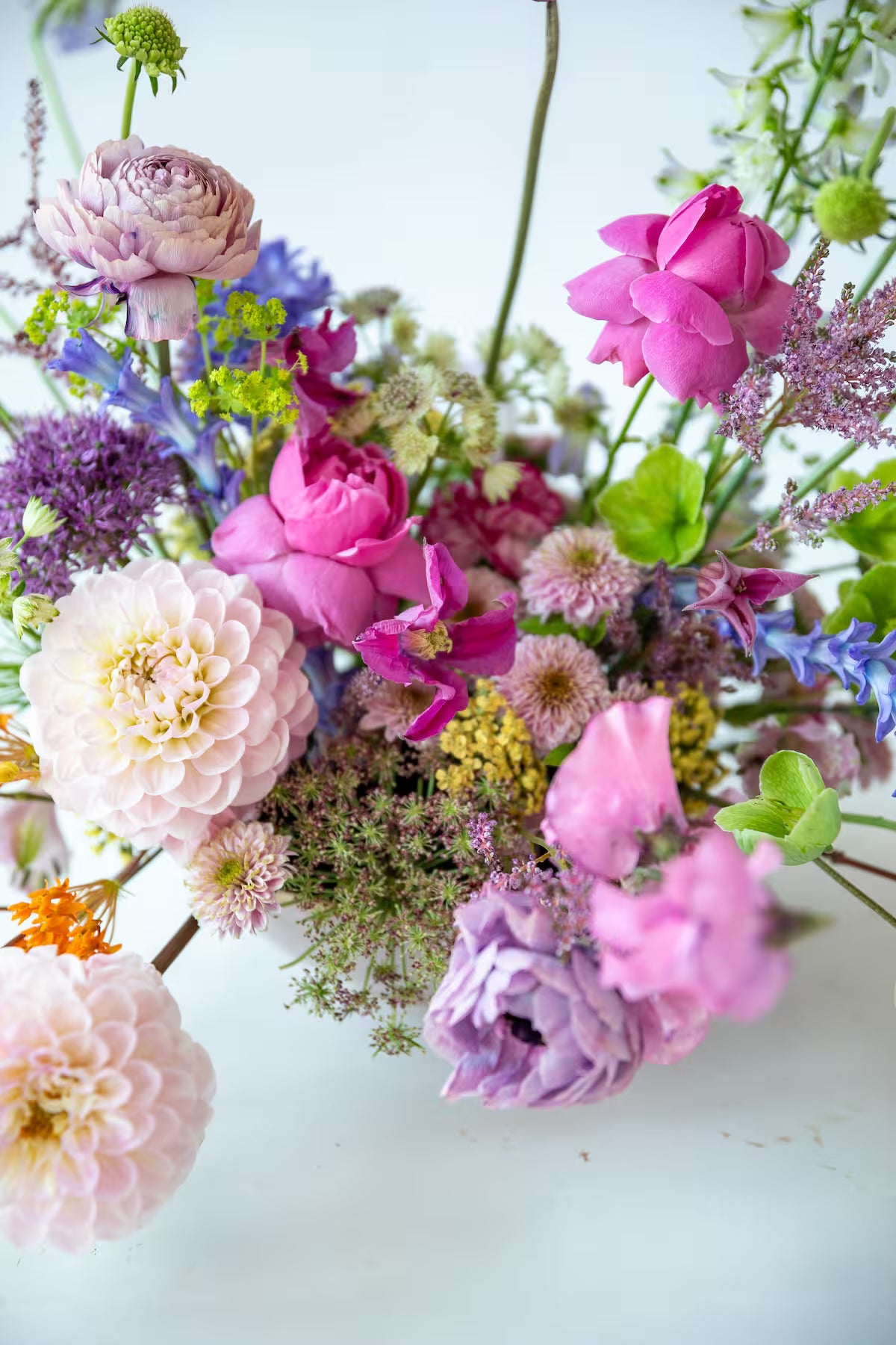 Primer plano de ramo con dalias blancas, rosas fucsias y ranúnculos lilas