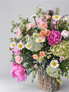 Arreglo floral variado con peonías rosas margaritas y hortensias en una cesta de mimbre sobre fondo gris