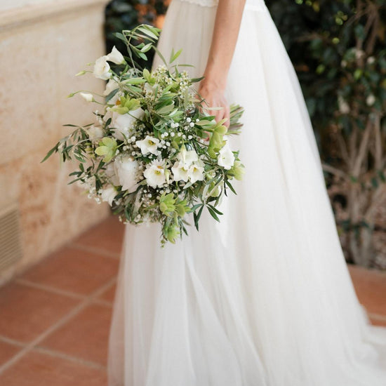 Novia con ramo de novia blanco y verde de eustoma, paniculata y ramas de olivo, vestido de tul