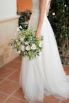 Novia con ramo de novia blanco y verde de eustoma, paniculata y ramas de olivo, vestido de tul
