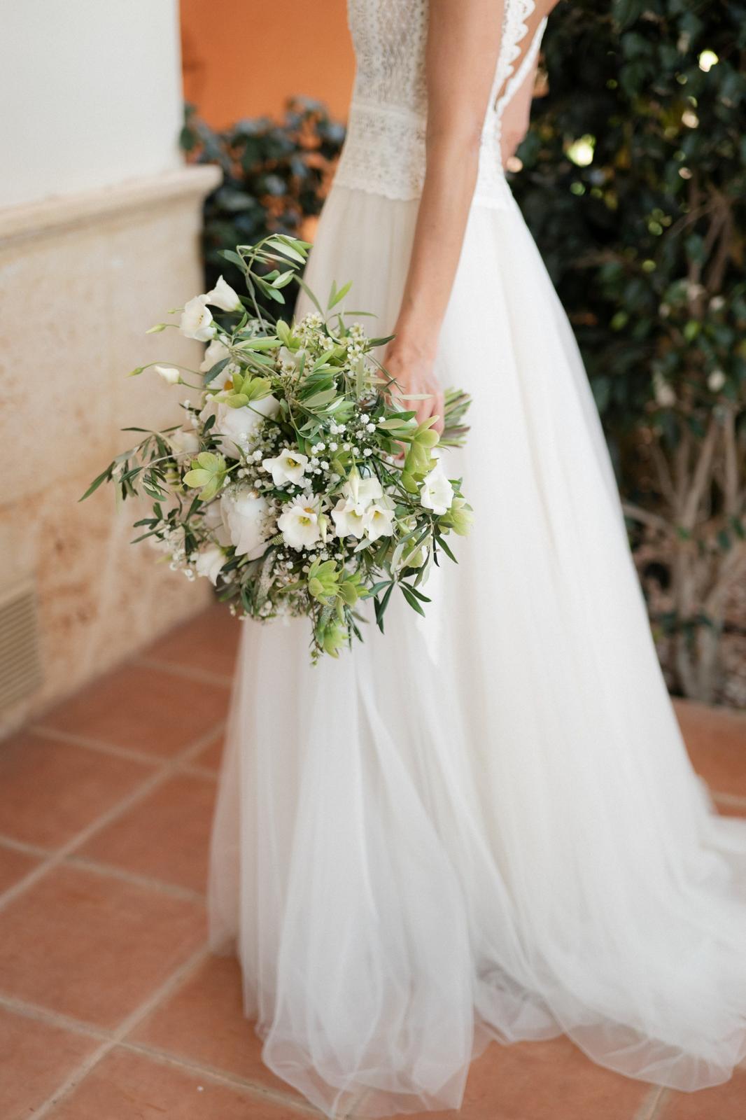 Novia con ramo de novia blanco y verde de eustoma, paniculata y ramas de olivo, vestido de tul