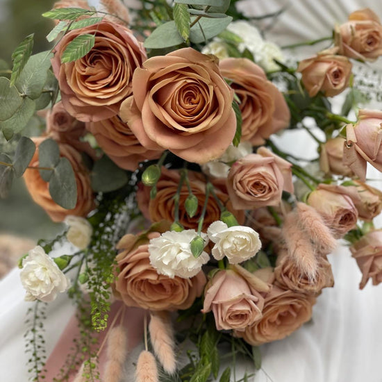 Detalle de ramo de novia con rosas capuchino, claveles blancos, lagurus rosa y eucalipto