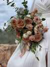 Ramo de novia con rosas color capuchino, claveles blancos, lagurus y eucalipto sobre vestido blanco