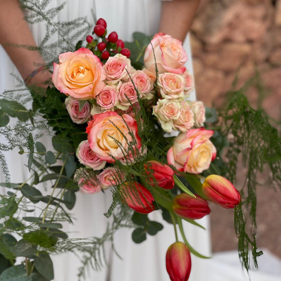 Detalle de ramo de novia con rosas melocotón y rosas ramificadas, tulipanes rojos e hypericum