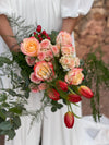 Detalle de ramo de novia con rosas melocotón y rosas ramificadas, tulipanes rojos e hypericum